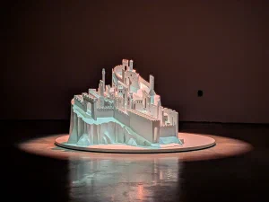 A white city model in the middle of a dark room illuminated from above