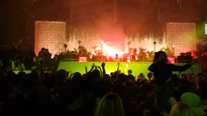 Crowd with hands raised in front of a DJ stage at a night event